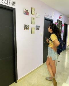 Una chica parada en un pasillo mirando su celular en Hostal Domi1949, en San Vicente de Chucurí