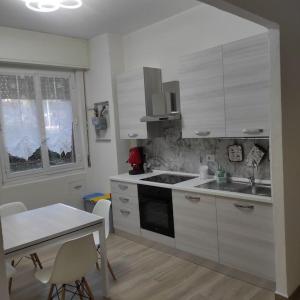 a kitchen with white cabinets and a sink and a table at Onda Marina 2 in La Spezia
