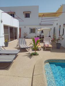 a patio with lounge chairs and a swimming pool at L'essentiel nianing in Mbour