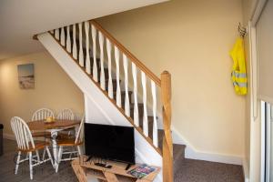 a living room with a table and a tv and a staircase at The Snug in Donegal