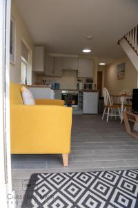 Una sala de estar con un sofá amarillo y una cocina. en The Snug, en Donegal