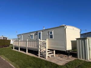 a gray and white trailer with a wooden deck at AMS Caravan Holidays in Ingoldmells
