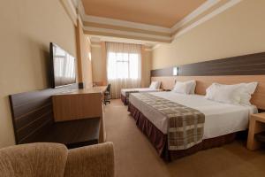 a hotel room with two beds and a desk at Hotel Executive Arapongas in Arapongas