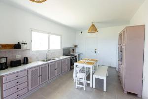 uma cozinha com armários brancos, uma mesa e um balcão em Beach house Hammamet em Hammamet Nord