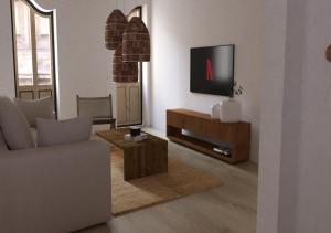 - un salon avec une télévision, un canapé et une table dans l'établissement El Refugi de Girona, à Gérone