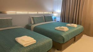 2 Betten in einem Hotelzimmer mit Handtüchern darauf in der Unterkunft Jeboutiquelangsuan hotel in Lang Suan
