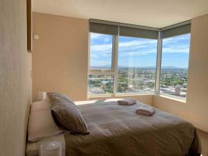 a bedroom with a large bed with a large window at Departamento 3 piezas Centro Chillan - Parking - Vista - Factura in Chillán