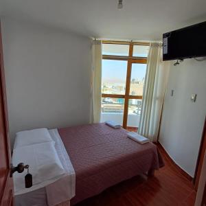 a small bedroom with a bed and a window at El Capricho II Paracas in Paracas