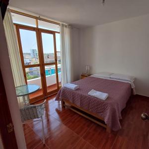 a bedroom with a bed and a large window at El Capricho II Paracas in Paracas