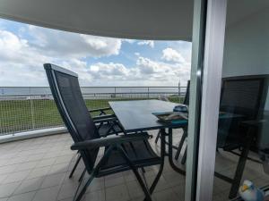 een tafel en stoelen op een balkon met uitzicht op de oceaan bij 033 Arngast Ferienwohnung in Wilhelmshaven
