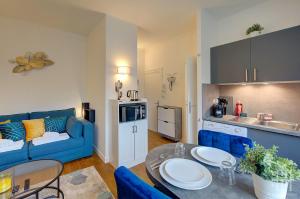 a living room with a blue couch and a kitchen at L'Agapanthe - Proche Gare in Saint-Pierre-des-Corps +6 photos