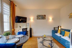 a living room with a blue couch and a table at L'Agapanthe - Proche Gare in Saint-Pierre-des-Corps