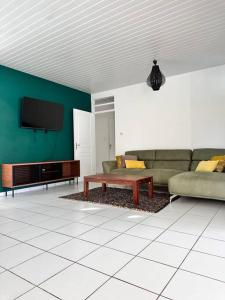 a living room with a couch and a tv at Villa Tropicana in Rémire-Camp