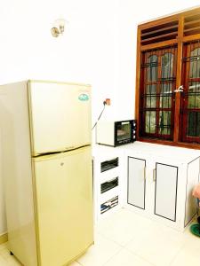 a kitchen with a refrigerator next to a window at Matara Near Polhena & Mirissa Three Story House in Matara