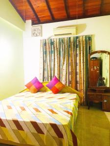 a bedroom with a bed with colorful pillows on it at Matara Near Polhena & Mirissa Three Story House in Matara