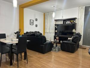 a living room with black leather furniture and a television at Departamento interior 1er piso. in Cajamarca
