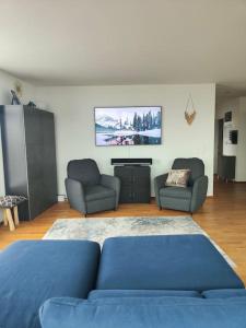 Switzerland Suite im 12. Stock في ثون: غرفة معيشة مع أريكة زرقاء وكرسيين