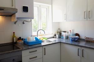 eine Küche mit weißen Schränken, einem Waschbecken und einem Fenster in der Unterkunft Vivenda Costa in Tondela