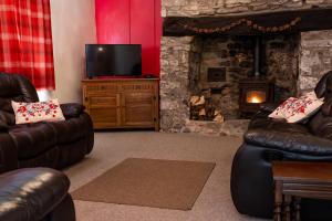 a living room with two leather couches and a fireplace at Pen-Y-Graig Cottage Brynamman in Brynamman