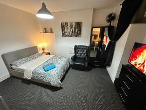 a bedroom with a bed and a chair and a television at Whitechapel Station Rooms R1 in London