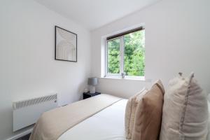 een witte slaapkamer met een bed en een raam bij The Peckham Collection in Londen
