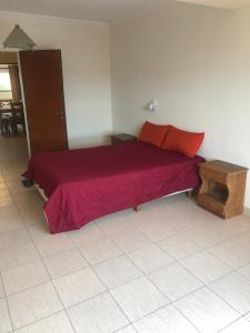 Schlafzimmer mit einem Bett mit roter Bettwäsche und einem Tisch in der Unterkunft Complejo Frente al Mar in Monte Hermoso