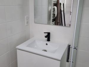 Baño blanco con lavabo y espejo en Gîte LES DUNES 47C, en Bricqueville-sur-Mer