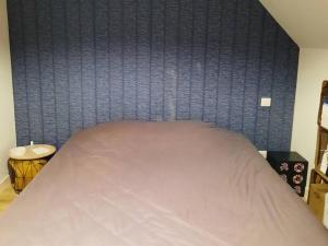 1 cama en un dormitorio con una pared azul en Gîte LES DUNES 47C, en Bricqueville-sur-Mer