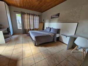 een slaapkamer met een bed en een tafel en stoel bij ZUCH Accommodation at Pafuri Self Catering - Guest Suite in Polokwane