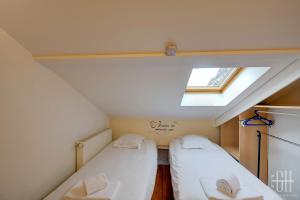2 Betten in einem kleinen Zimmer mit Dachfenster in der Unterkunft HALTE 6 / Monts in Monts