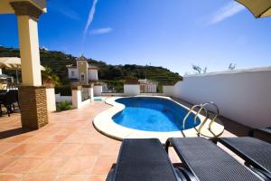 a swimming pool on a patio with chairs next to a building at Nerja Villas Tamango Hill 5 Silhouse in Torrox