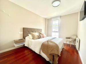 a bedroom with a bed with white sheets and a window at Piso Vistas O Son in Cee +16 photos