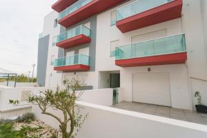 an apartment building with red balconies and a garage at Best Houses 104 - Supertubos Beach Apartment in Atouguia da Baleia