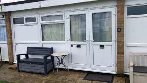a garage with white doors and a chair and a table at Oriental Belle Aire in Hemsby