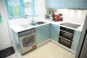 a kitchen with blue cabinets and a sink and a dishwasher at Reeve House - 2-Bed - FREE Parking & Wi-Fi in Kenilworth