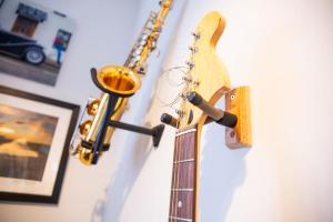 eine Gitarre hängt an einer Wand neben einem Saxophon in der Unterkunft Reeve House - 2-Bed - FREE Parking & Wi-Fi in Kenilworth