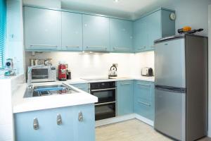 eine Küche mit blauen Schränken und einem Kühlschrank aus Edelstahl in der Unterkunft Reeve House - 2-Bed - FREE Parking & Wi-Fi in Kenilworth