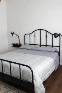 a bedroom with a bed with a black frame and white sheets at Casa Delisa in Ceggia