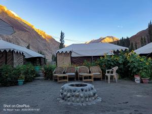 un gruppo di sedie, un tavolo e un grande pneumatico di Tyakshi Summer Camp a Valle di Nubra