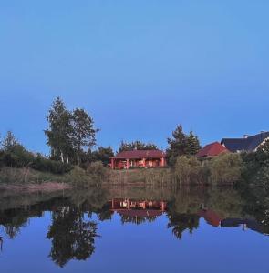 a red house sitting on top of a lake at W Sosnach in Tokarnia