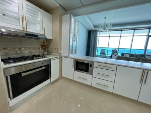 uma cozinha com armários brancos e um forno com placa de fogão em Luxurious Sea View - Beach Front em Ajman