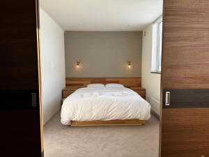 - une chambre avec un grand lit et des draps blancs dans l'établissement Mountain Villa ニセコ, à Kutchan