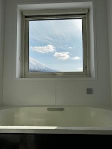 a window in a bathroom with a view of a mountain at Mountain Villa ニセコ in Kutchan