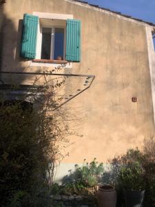 un bâtiment avec une fenêtre et un volet vert dans l'établissement Maison de village en Provence, calme et ensoleillée, à Villedieu