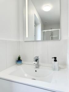 een witte badkamer met een wastafel en een spiegel bij LA CROIX BLANCHE - Proche Hôpital - Parking in Mont-de-Marsan
