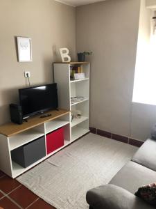 a living room with a tv on a white shelf at Casa Belia in Mansilla de las Mulas