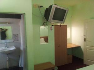 a bathroom with a sink and a tv on the wall at Brakendene Lodge in Gaborone