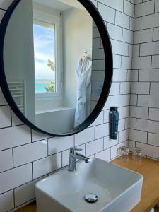 - un miroir au-dessus d'un lavabo dans la salle de bains dans l'établissement Hôtel Les Costans, The Originals Relais, à Perros-Guirec