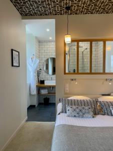 a bedroom with a bed and a bathroom with a sink at Hôtel Les Costans, The Originals Relais in Perros-Guirec
