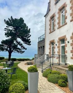 ein Gebäude mit einem Baum neben einem Gehweg in der Unterkunft Hôtel Les Costans, The Originals Relais in Perros-Guirec